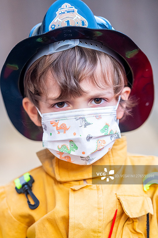 万圣节消防员装扮的严肃小男孩戴着防护口罩看着镜头图片素材
