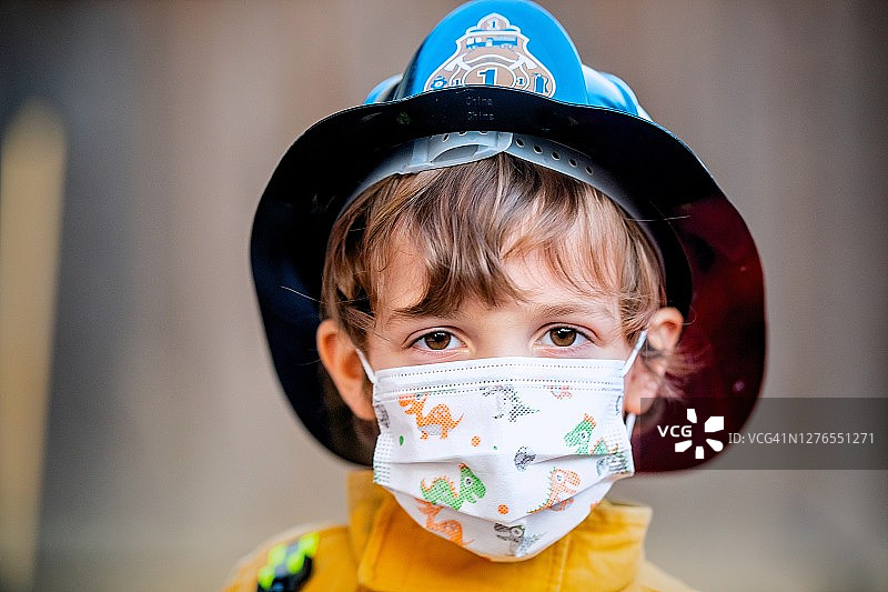 万圣节消防员装扮的严肃小男孩戴着防护口罩看着镜头图片素材