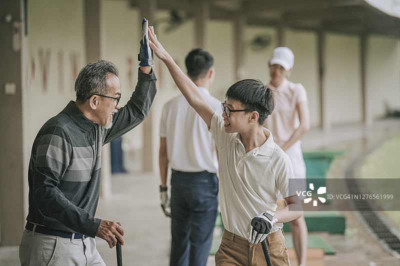 高尔夫球场上与孙子击掌庆祝的华人爷爷图片素材