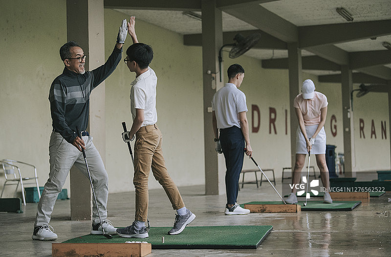 高尔夫球场上与孙子击掌庆祝的华人爷爷图片素材