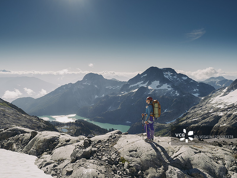 在阿尔卑斯湖泊上方徒步旅行的女性登山者图片素材