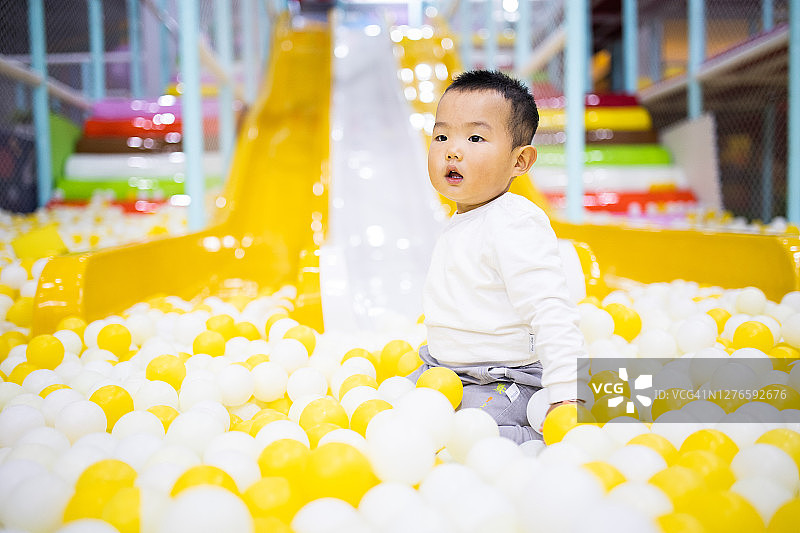 儿童在游乐场球池里玩彩色球图片素材