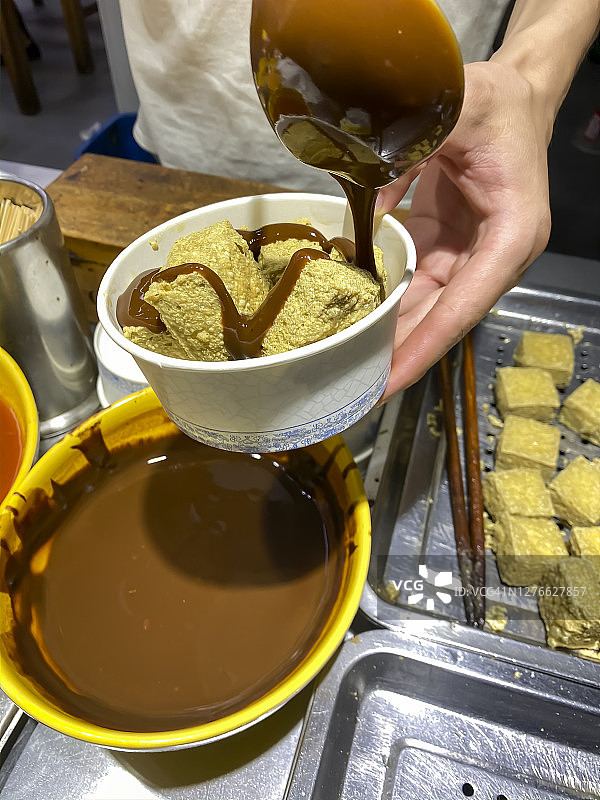 男人将甜面酱淋在炸豆腐上图片素材