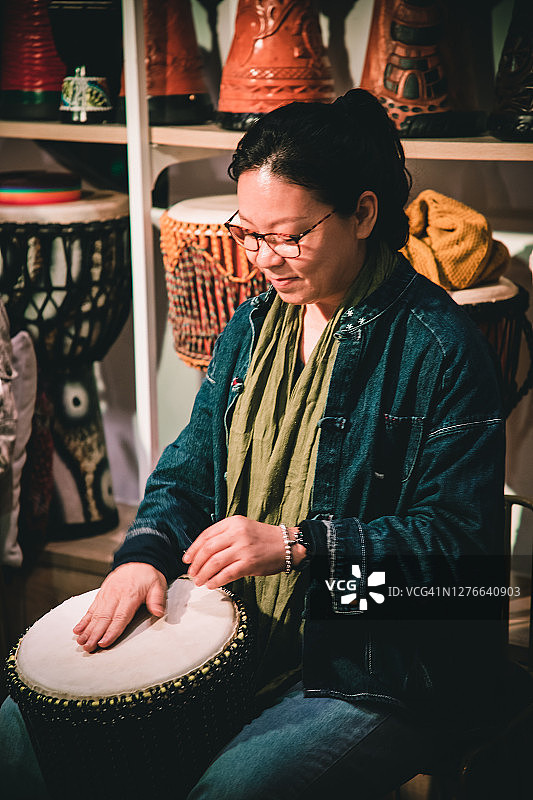 年长的亚洲女人在户外演奏邦戈鼓图片素材