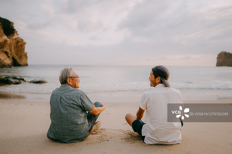 年长的父亲和儿子在日落时分的海滩上愉快地玩耍图片素材