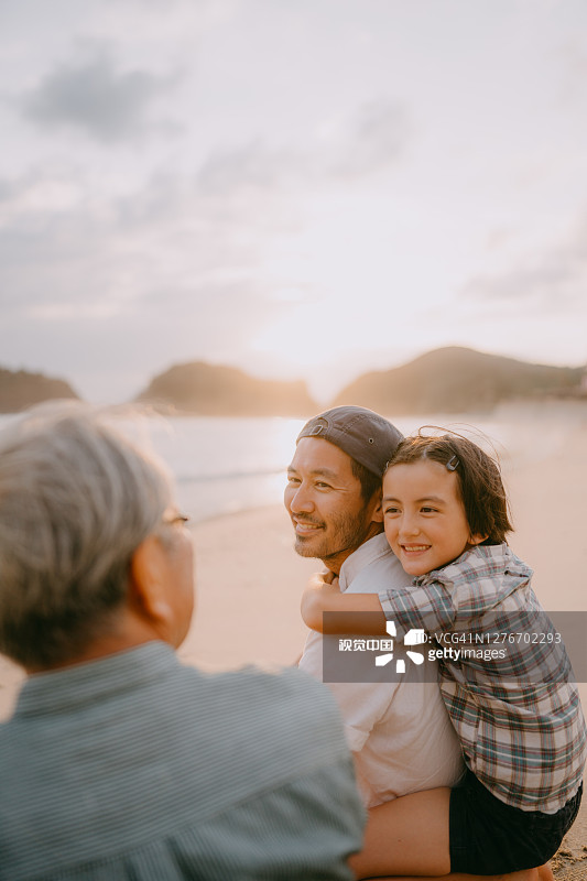 三代同堂家庭在日落时分的海滩上共度美好时光图片素材