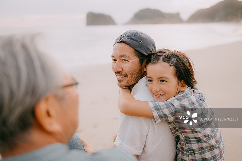 三代同堂家庭在日落时分的海滩上共度美好时光图片素材