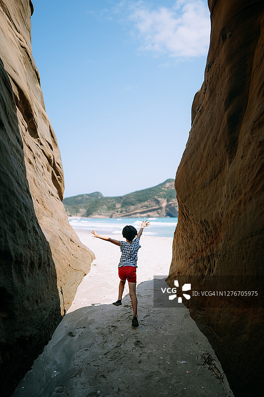 从洞穴跑向海滩的年轻女孩图片素材