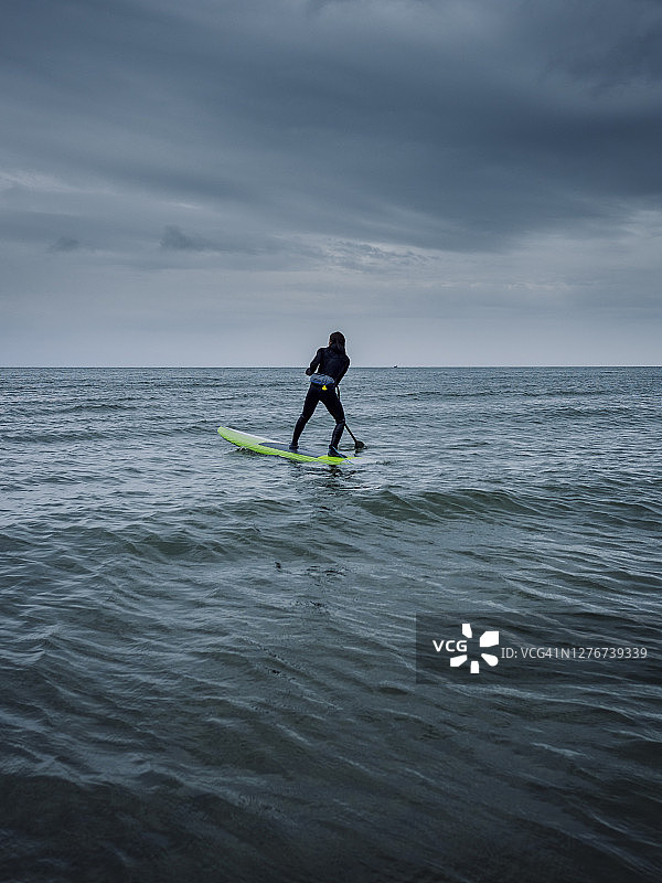 在不列颠哥伦比亚阳光海岸，女子在暴风雨天气中玩桨板冲浪图片素材