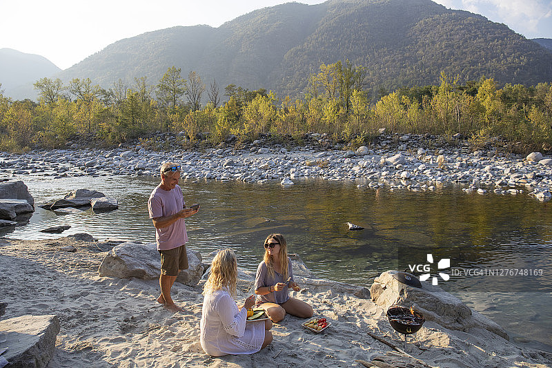一家人和成年女儿在日落时分在河边烧烤图片素材