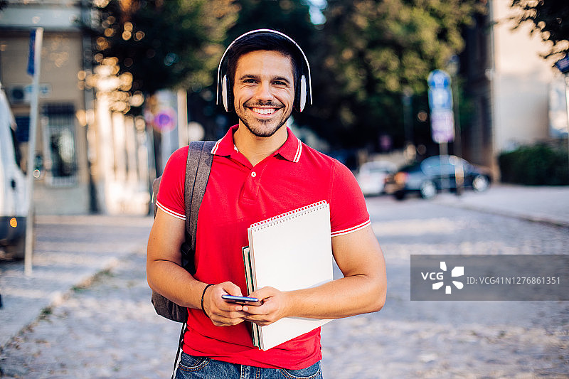 一位英俊的学生在旅途中听音乐的肖像照图片素材