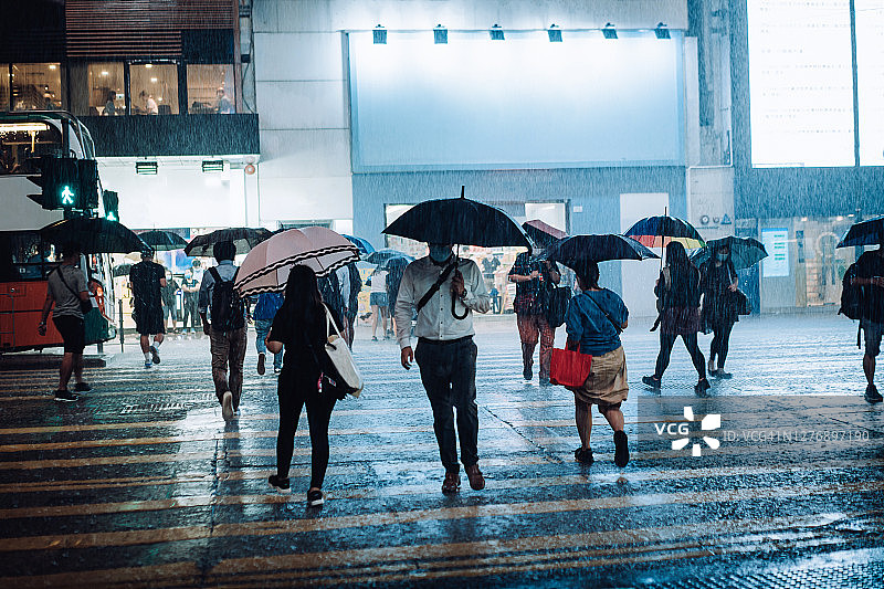 戴口罩的人群在市中心冒雨过马路图片素材