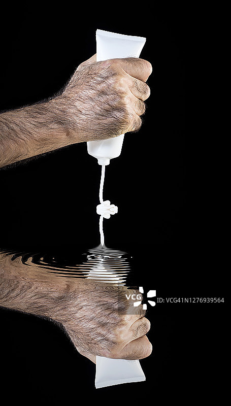 黑色背景上拿着滋润护手霜的男人的手图片素材