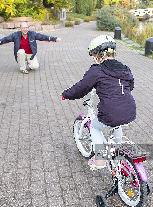 在秋日公园里散步的一家白人，父女和骑自行车的孩子图片素材