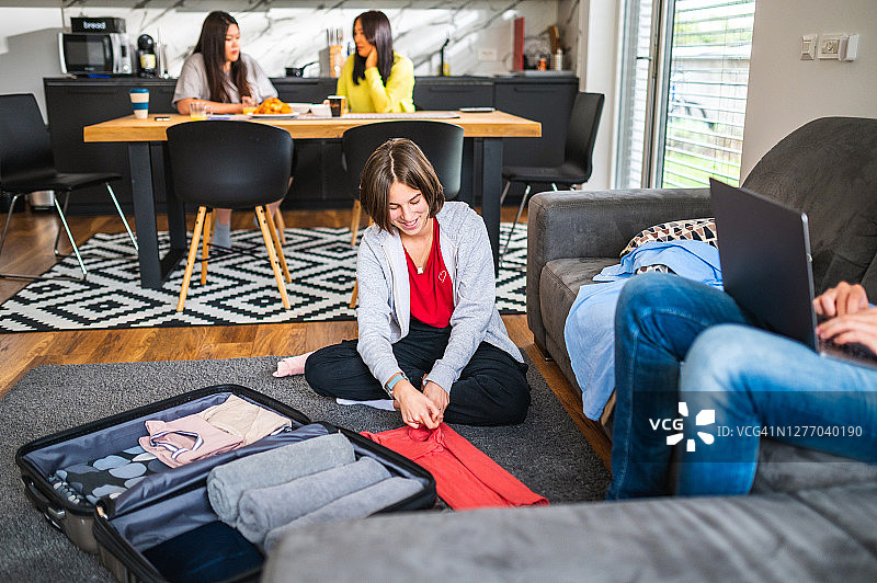 白人少女在客厅里把衣服装进手提箱图片素材