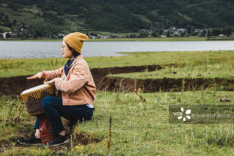 亚洲女性在野外户外演奏邦戈鼓图片素材