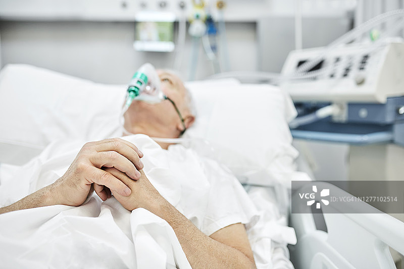 在担架上祈祷的冠状病毒老年患者图片素材