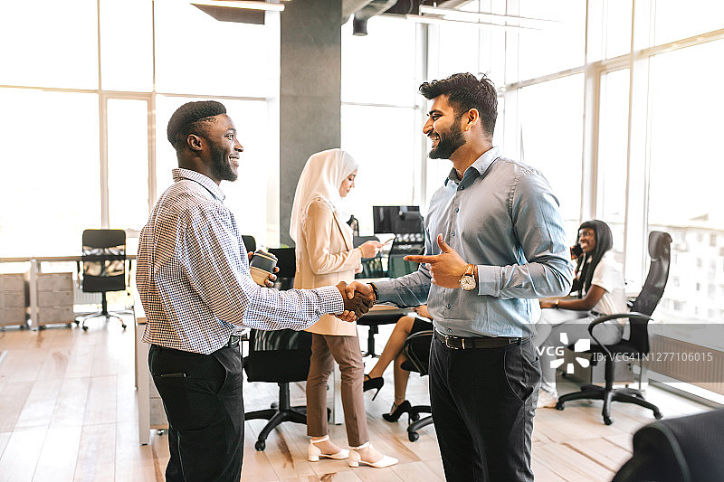 微笑的非洲裔和印度裔商人签署合同后握手图片素材