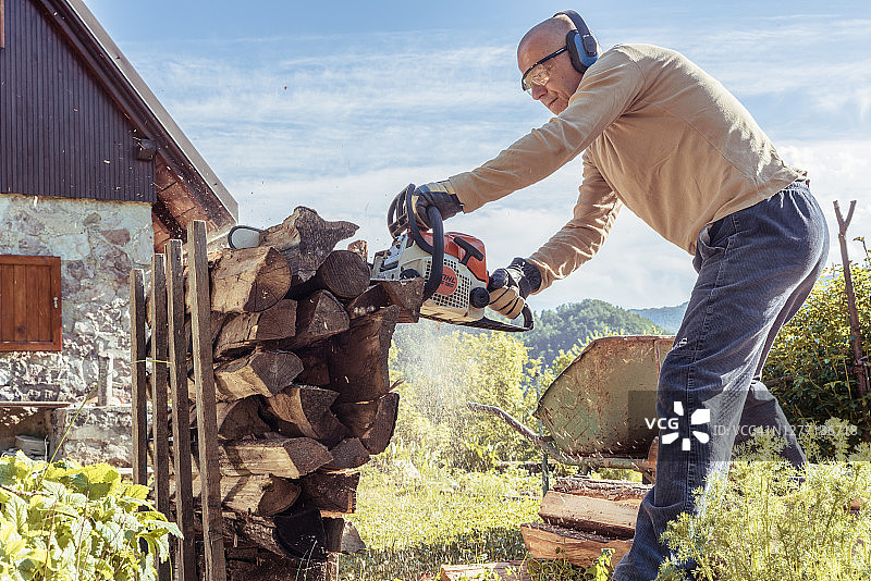 男人用油锯为供暖季节准备木柴图片素材