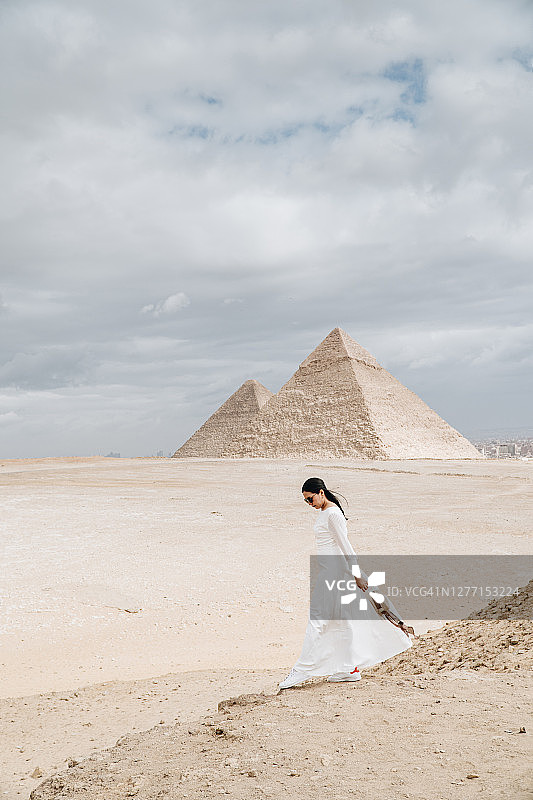 穿着白色连衣裙站在吉萨大金字塔前的女人图片素材