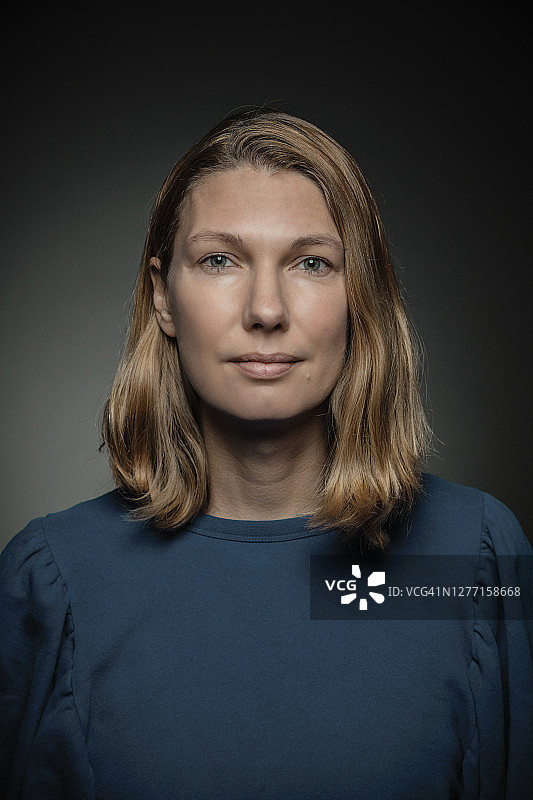 站在灰色背景前的金发女人图片素材