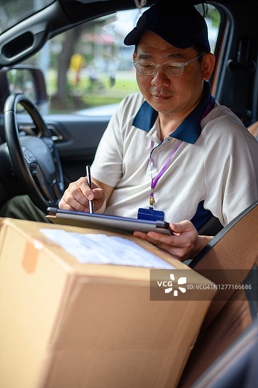 亚洲送货员在平板电脑上查看清单图片素材