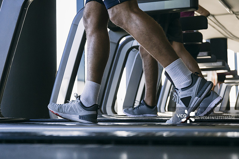 运动员在健身俱乐部跑步机上跑步的腿图片素材