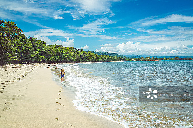 在田园诗般的海滩上留下脚印的女孩图片素材