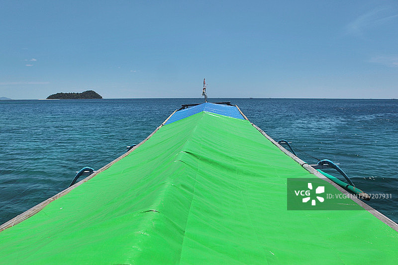 平静海面上航行的带绿色塑料顶棚的木船图片素材