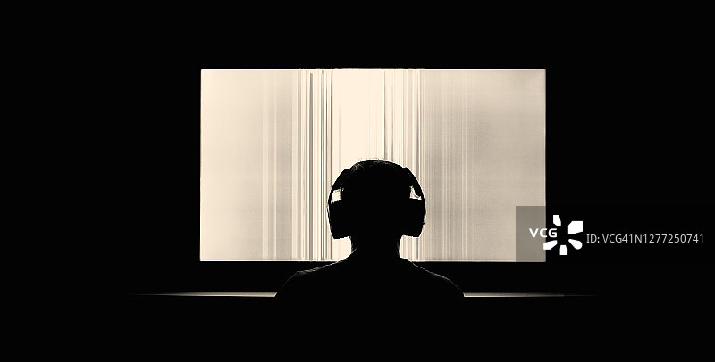 戴着耳机观看大电视屏幕的人图片素材