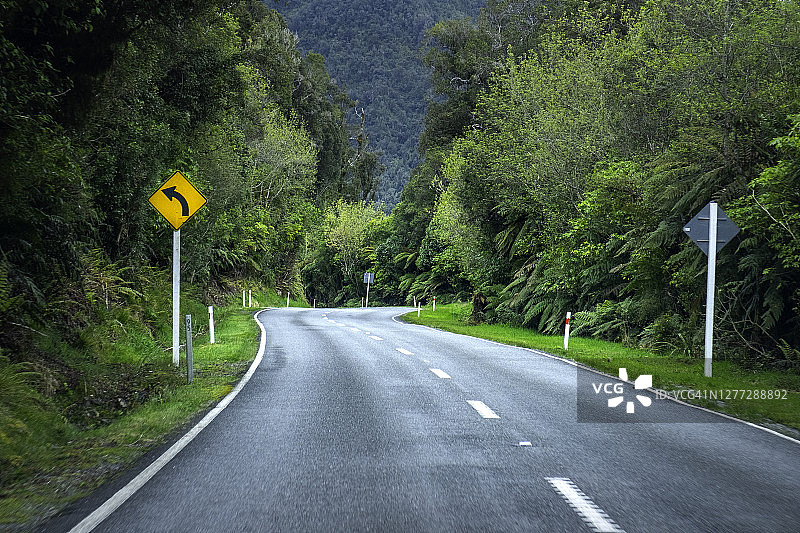 新西兰南岛西海岸的空旷道路和带有热带雨林的道路标志景象图片素材