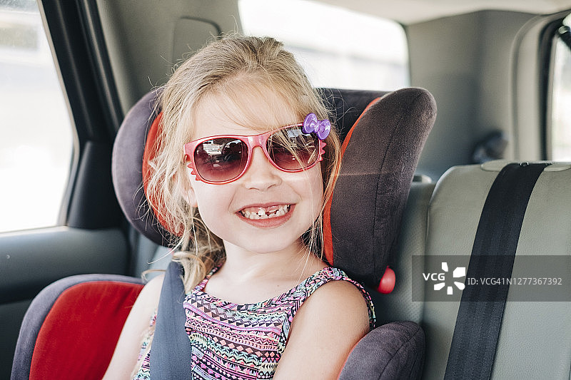 戴墨镜坐在汽车座椅上的年轻女孩图片素材