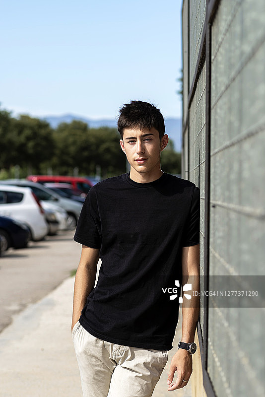 倚靠在金属栅栏上，看向镜头的年轻人图片素材