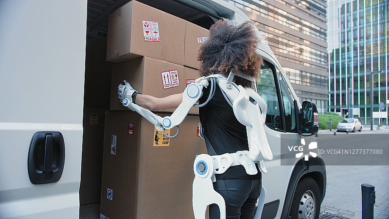穿着动力外骨骼搬家的职业女性，从卡车上搬运重物图片素材
