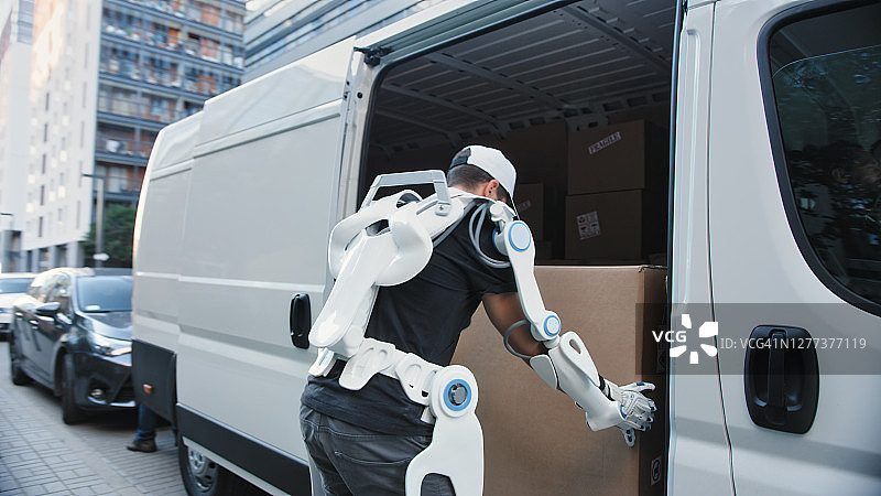 身穿动力外骨骼的专业搬运工从卡车上搬运重物图片素材