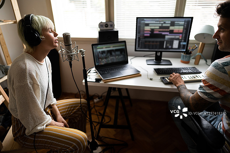 女歌手在音乐工作室与制作人一起演唱新歌图片素材