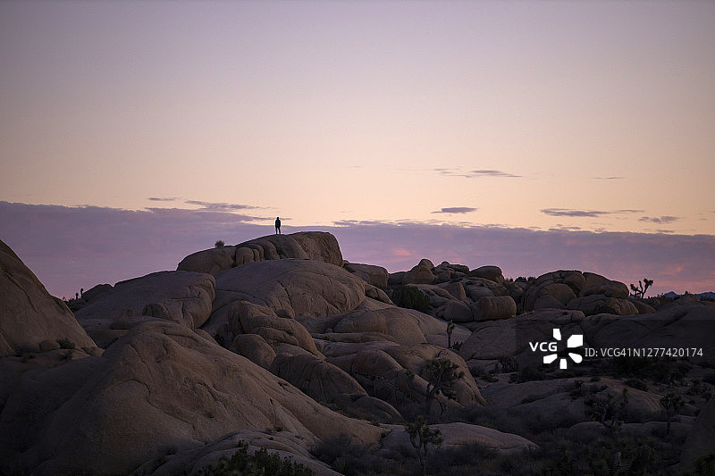 男子站在岩石上观看沙漠日落图片素材