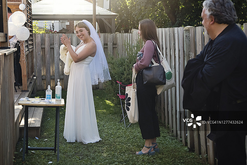 疫情期间新娘在后院婚礼鸡尾酒会前使用洗手液图片素材