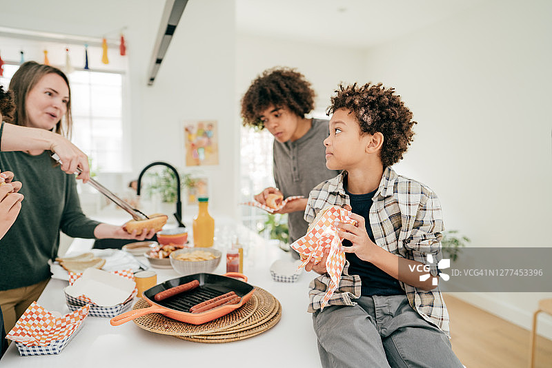 妈妈和孩子们在厨房里享用香肠午餐图片素材