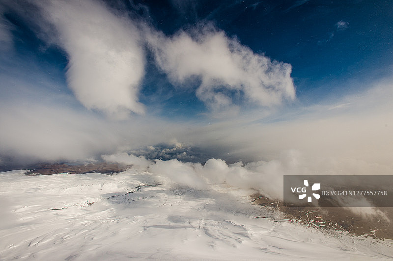 白雪覆盖的贫瘠土地和高耸云朵的俯瞰图图片素材