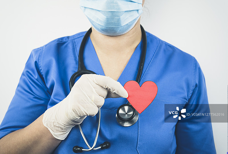 女医护人员穿着手术服，手持心形设备，白色背景肖像图片素材