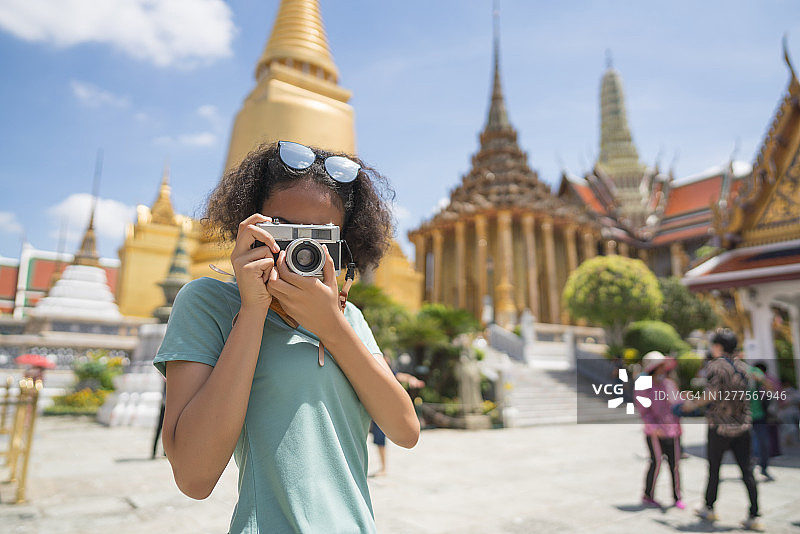 年轻女游客在泰国曼谷的玉佛寺用胶片相机拍照图片素材