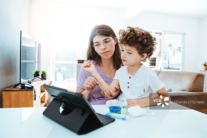 通过视频会议进行医疗咨询，演示如何处理儿童的伤口并准备敷料图片素材