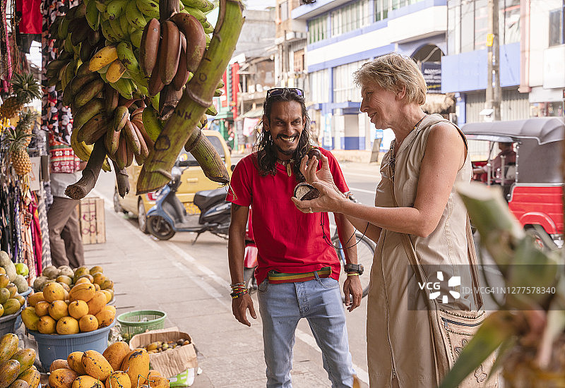 斯里兰卡阿卢特加马当地街头市场，斯里兰卡导游帮助欧洲女游客采摘新鲜水果图片素材