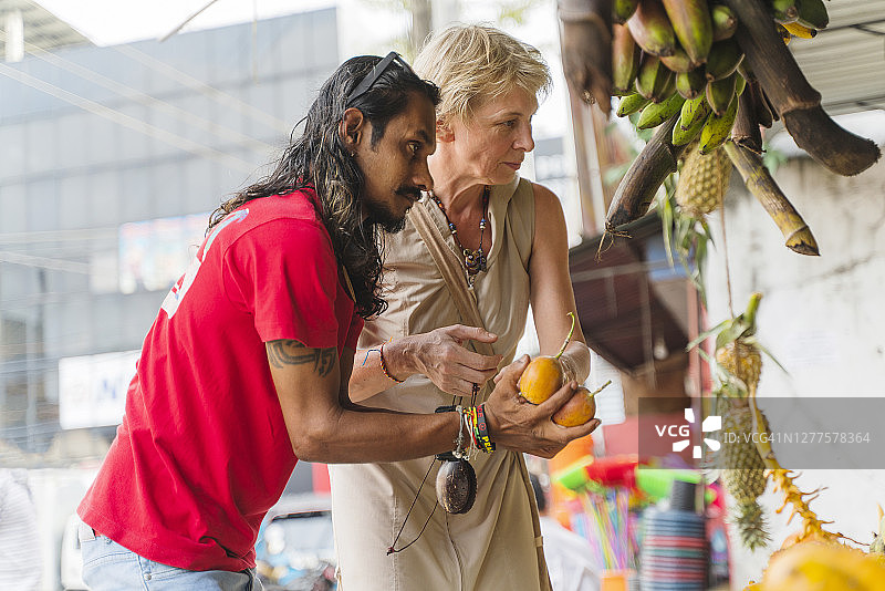 斯里兰卡阿卢特加马当地街头市场，斯里兰卡导游帮助欧洲女游客采摘新鲜水果图片素材