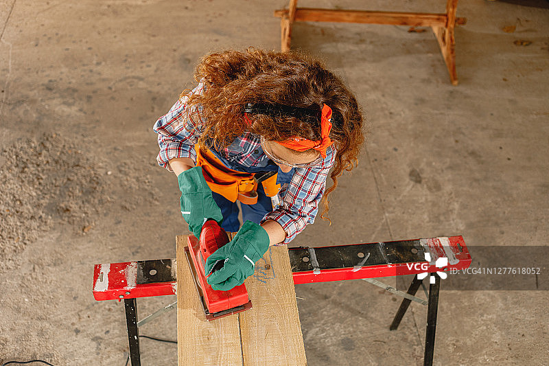 年轻女木匠打磨木板图片素材