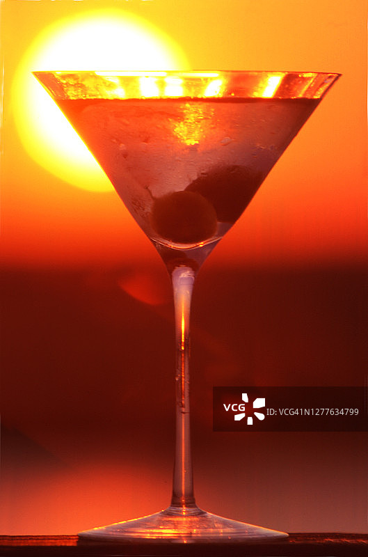 曼哈顿鸡尾酒和樱桃的抽象特写，背景是落日图片素材