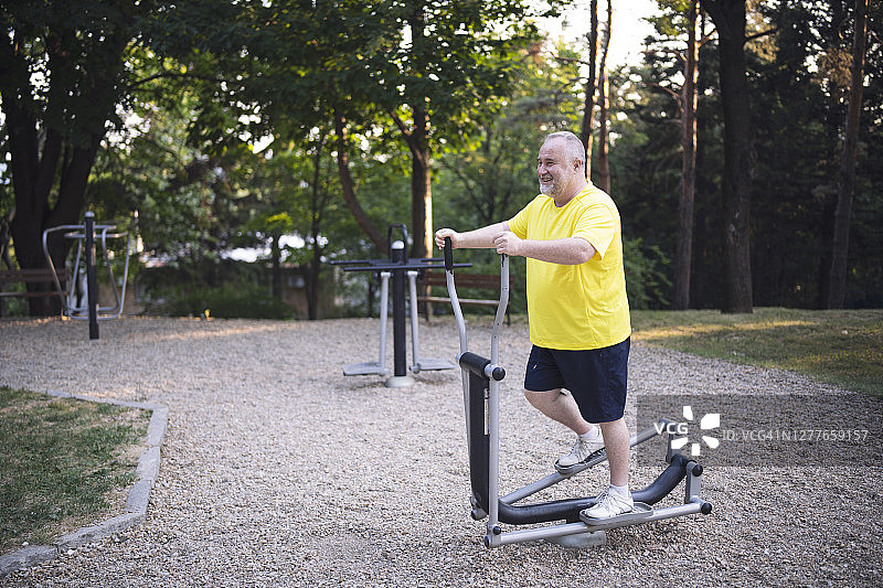 快乐的老年男性正在使用户外健身器材进行训练图片素材