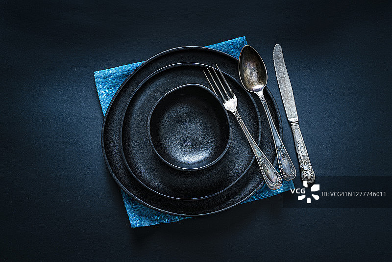 深色餐桌上的黑色餐具摆放（俯视）图片素材