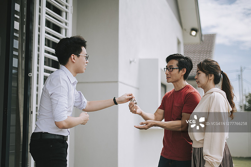 一对华人夫妇从房产中介手中接过新房钥匙图片素材